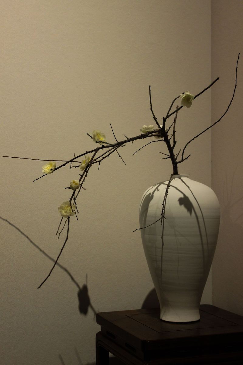 花の咲いた枝を一本挿した、白い花入